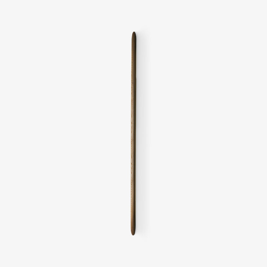 Slim tapered walnut rod mounted flat on a pale wall, seen unlit