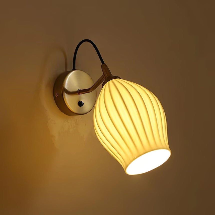 The fluted shade lit warm on a dark wall, the ribs glowing