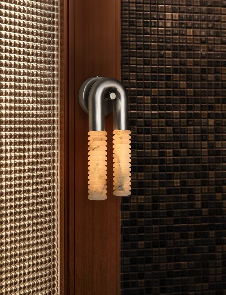 The sconce lit beside a woven wall panel and a dark wood door frame