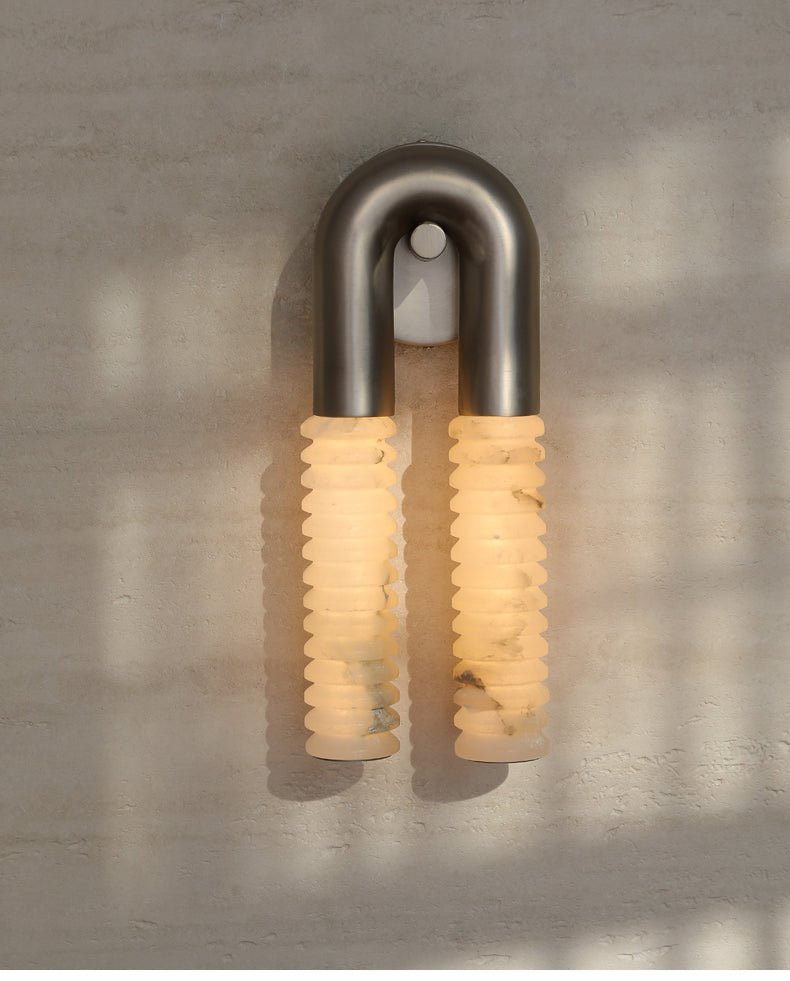 The lit sconce on a sunlit plaster wall with soft window shadows