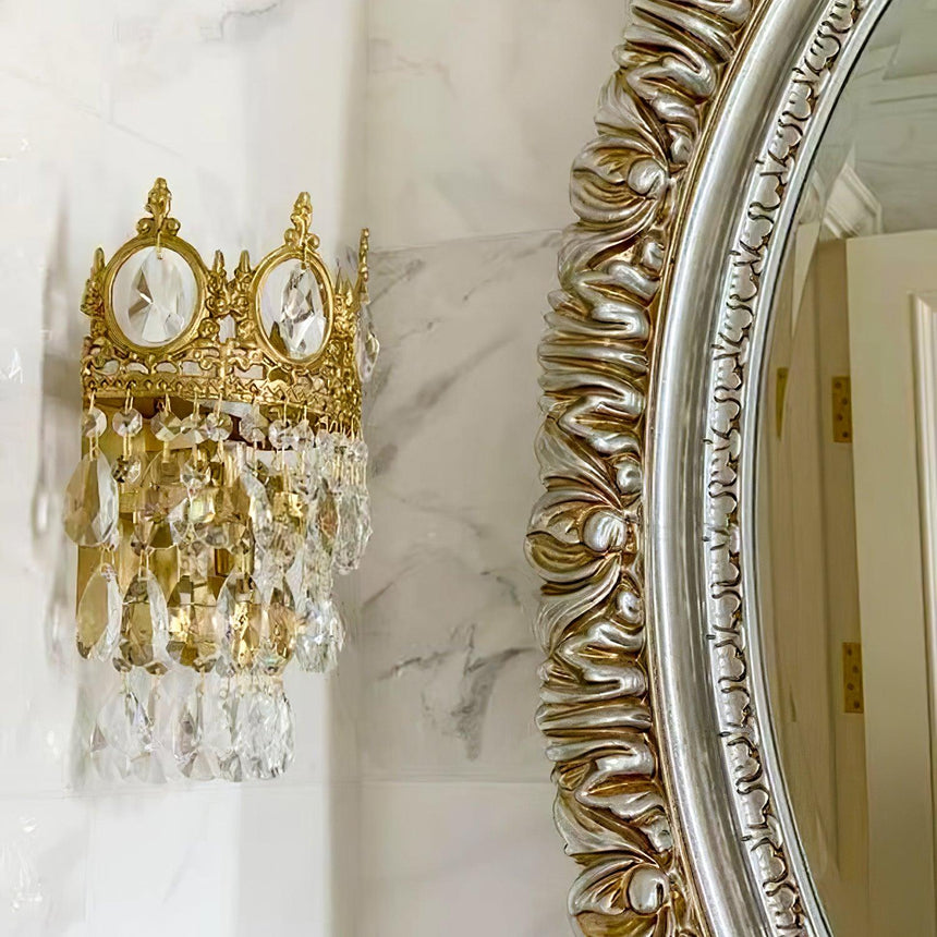 The crown lamp on a marble wall beside an ornate silver mirror frame
