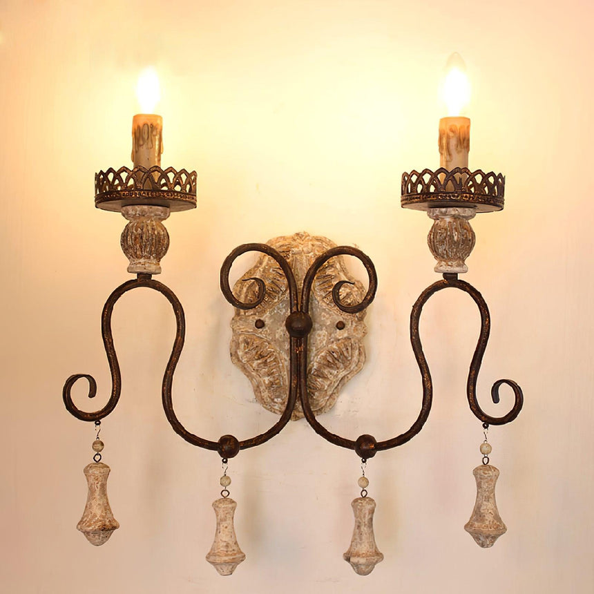 Two candle lamps lit warm on the iron arms above the carved wood plate
