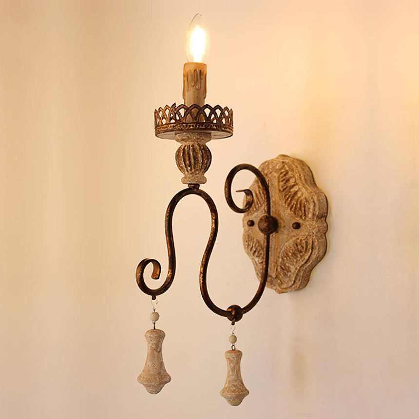 The two arm sconce lit, the carved wood plate glowing behind the flames