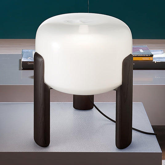 Frosted glass table lamp lit close, the glass drum glowing evenly