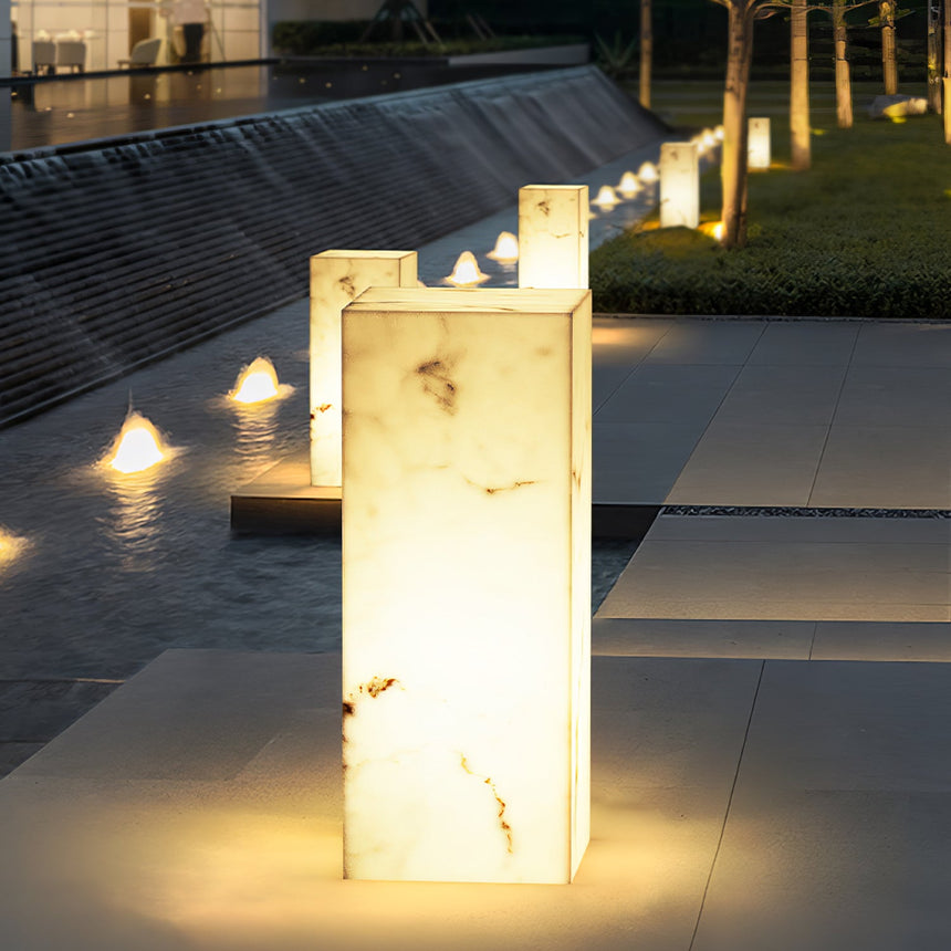 Two lit at the edge of a still water channel with paving beyond