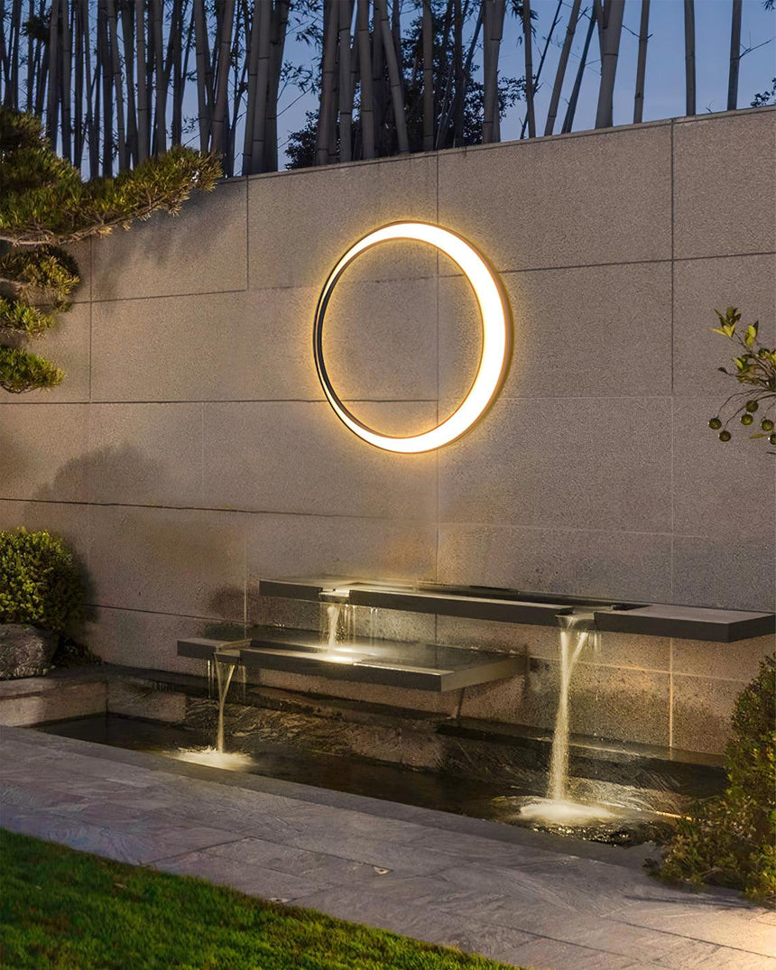 The ring lit on a garden wall above a stepped water feature and a lawn