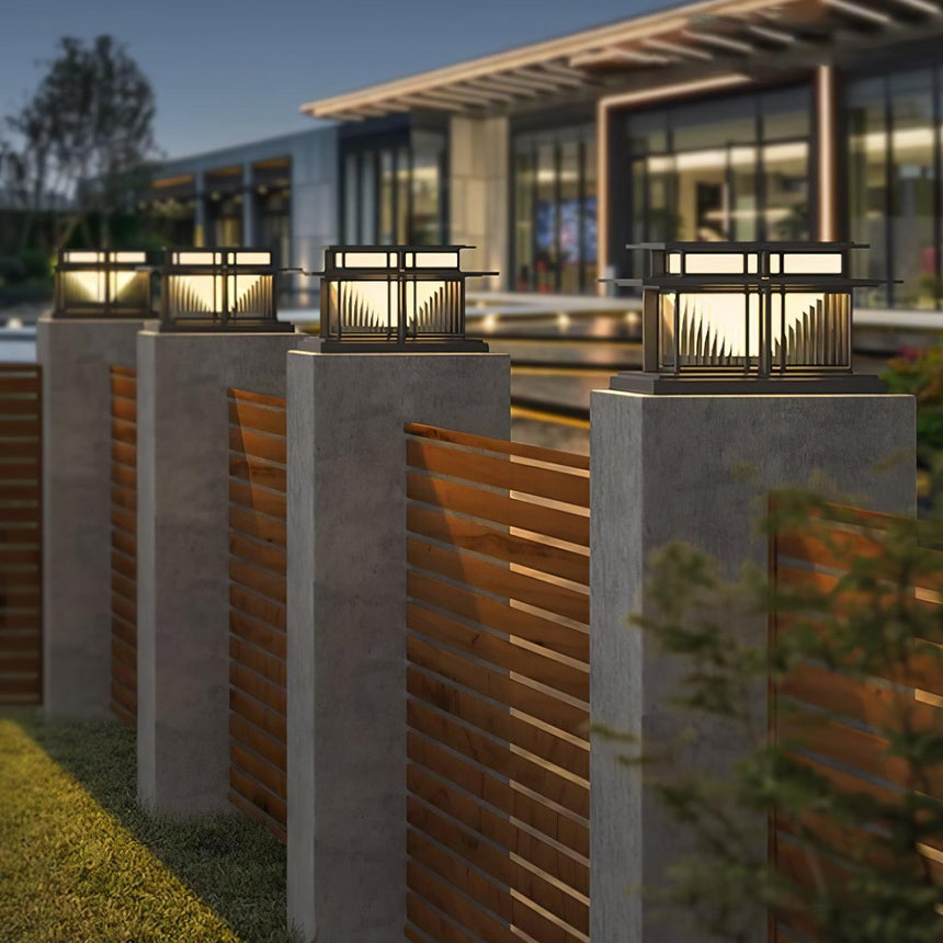 Caps lit on pillars framing a timber slat gate on a dark driveway