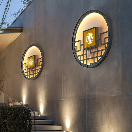 Two round lattice lights on a gray garden wall above stone steps lit by small uplights