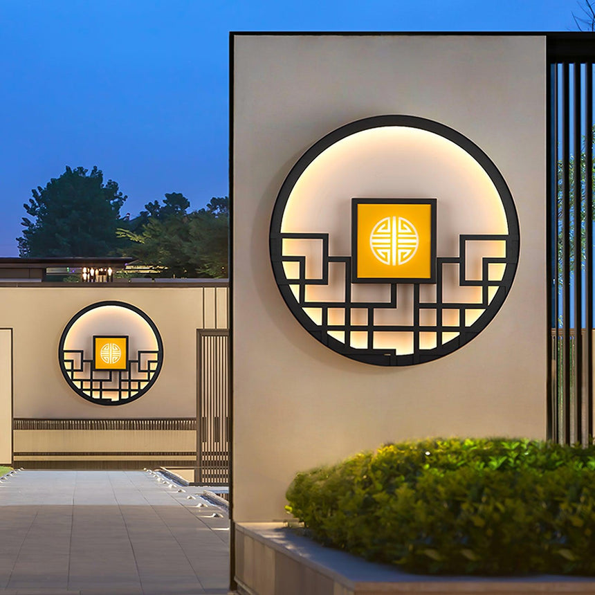 Two round lights on entrance walls, one large above a hedge and one smaller behind