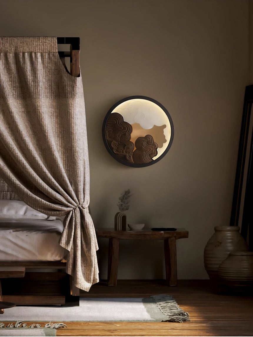 Sconce lit beside a long curtain above a bench and a tall floor vase