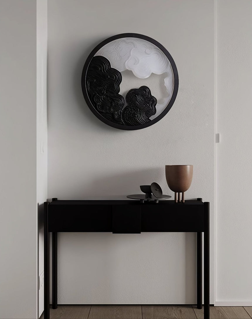 Sconce lit above a narrow black console holding two pale stone bowls