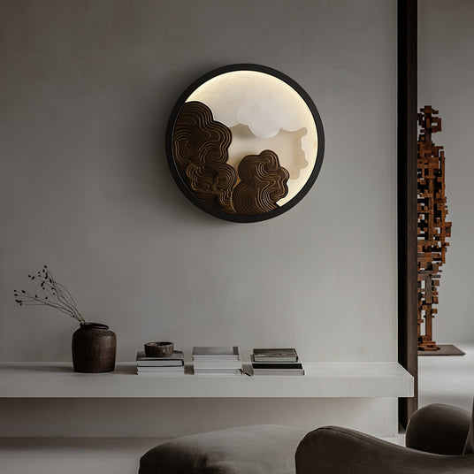 Sconce lit above a long console beside a low sofa and a stone vase