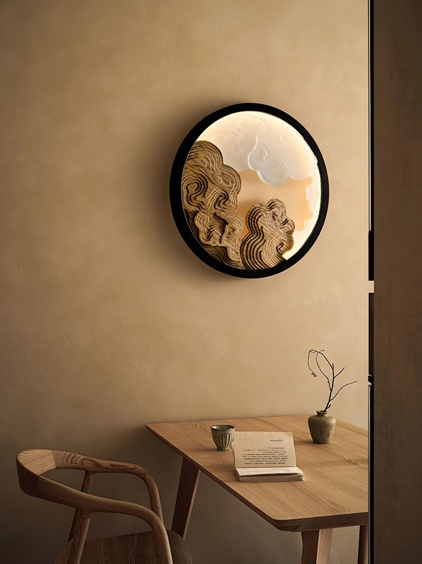 Sconce lit above a wood table with an open book and a pale chair