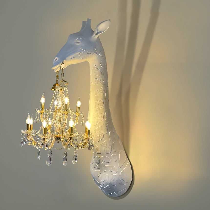 The chandelier candles lit warm below the white giraffe head