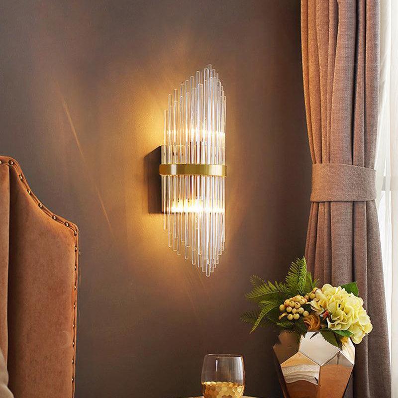The sconce lit on a brown wall beside a curtain and a vase of yellow flowers