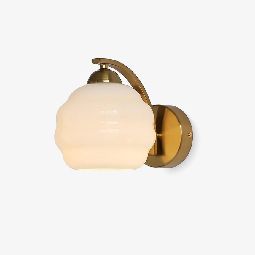 Wall sconce with a curved gold arm holding a white ribbed glass globe