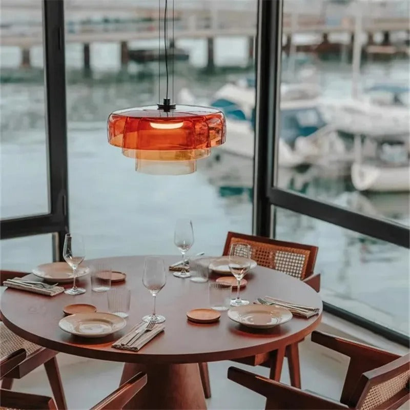 Orange stacked glass shade above a round table by a marina window