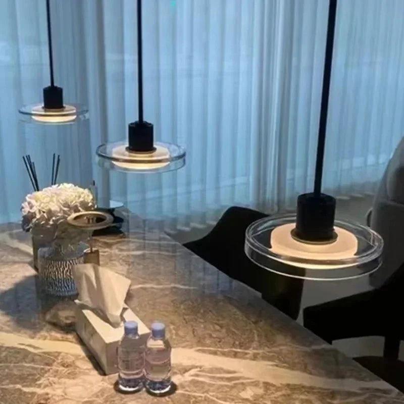 A disc pendant lit above a marble counter with a vase of white flowers