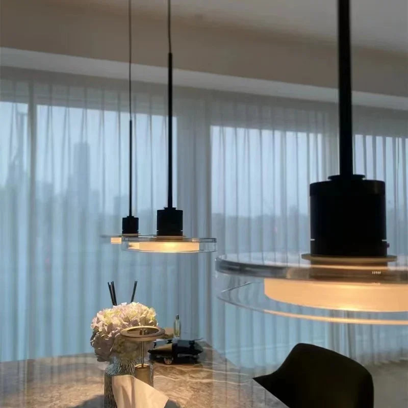 Two disc pendants above a dining table in front of a sheer curtained window