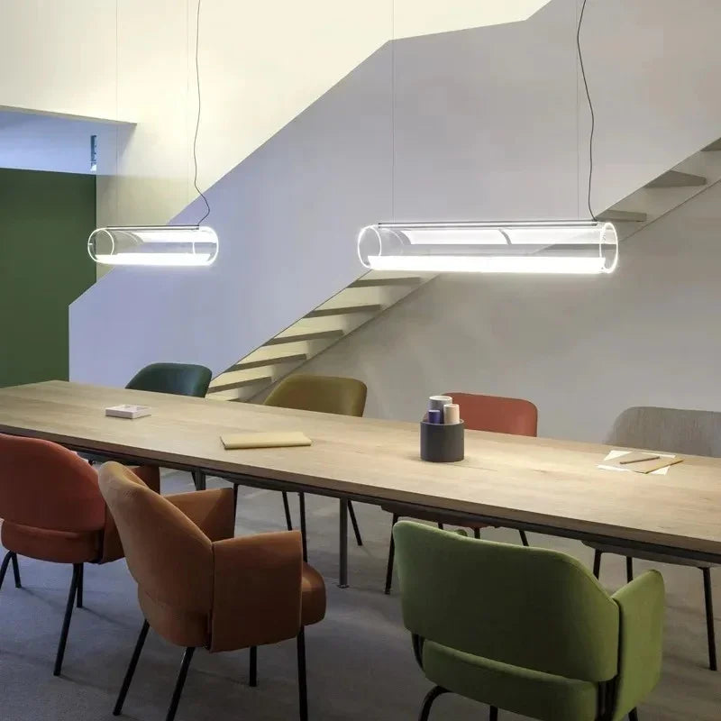 Two tubes lit in a row above a long meeting table with coloured chairs