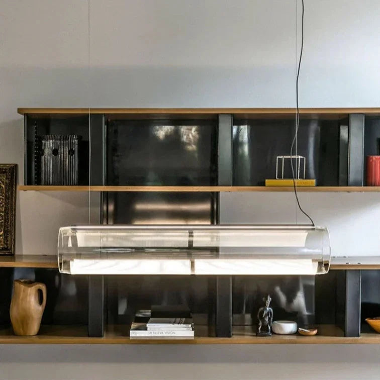 The tube lit in front of a dark shelving wall above a long counter