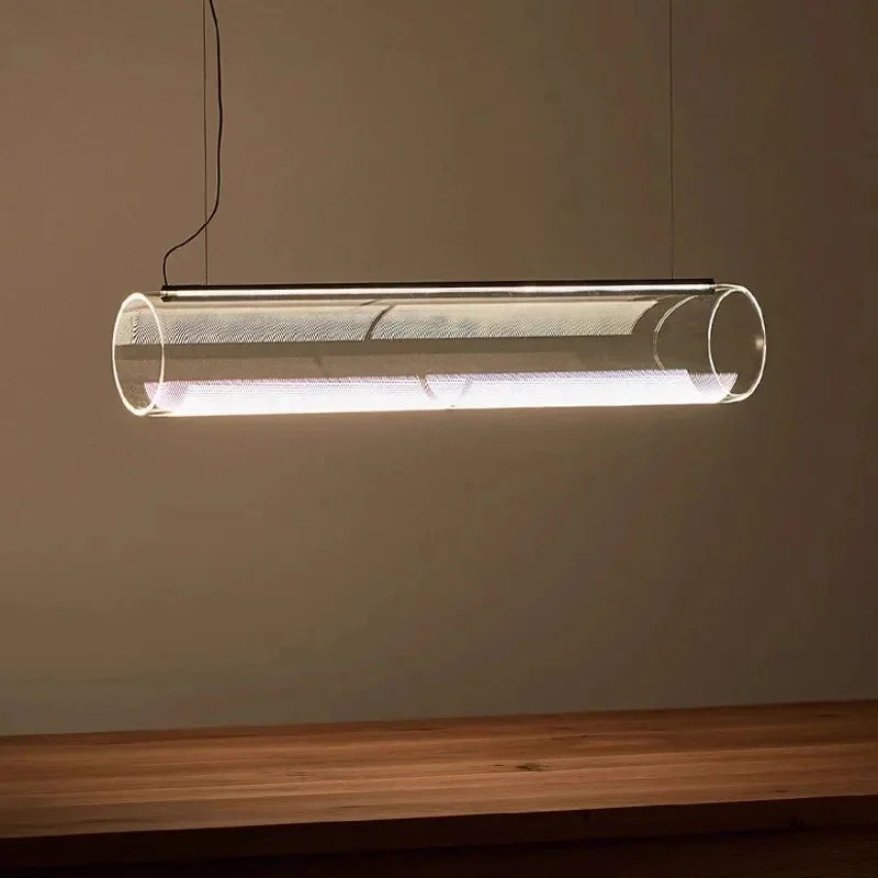 A horizontal glass tube lit above a pale table in a warm toned room
