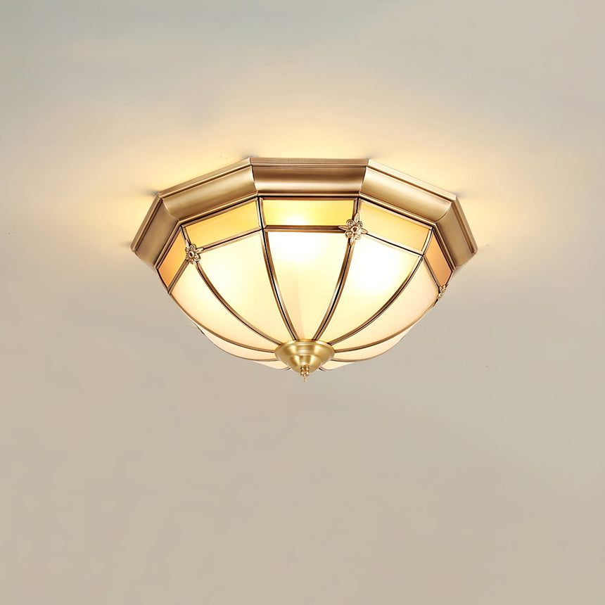 Faceted brass dome ceiling light seen from the side, lit