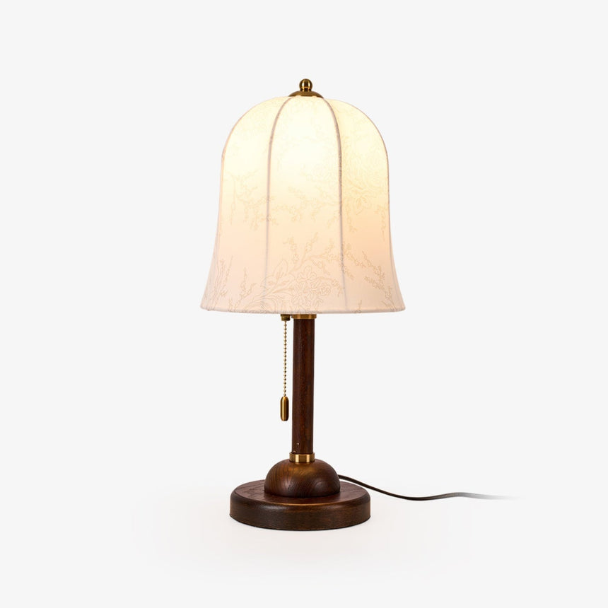 Gold and white table lamp with a bell shade on a walnut stem