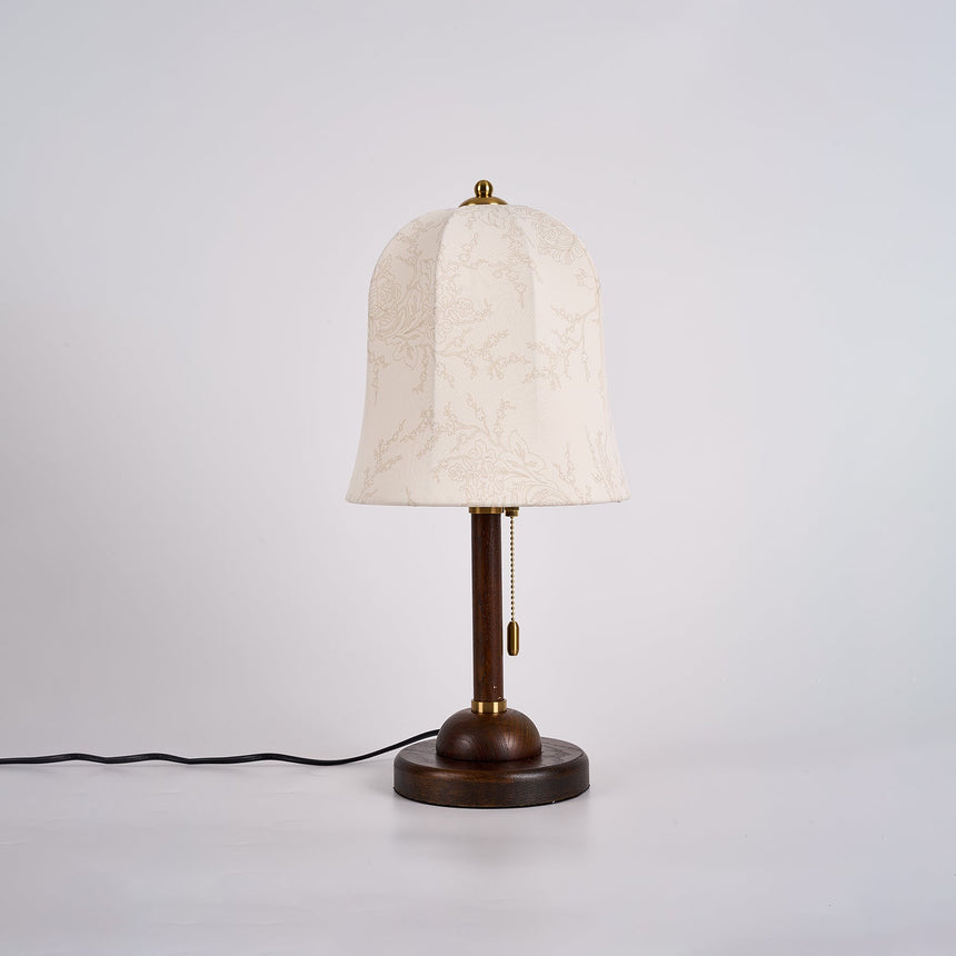 Gold and white table lamp unlit, the floral print on the shade visible