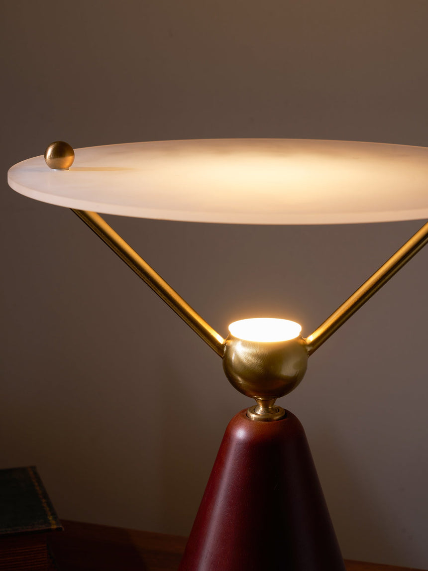 The lit underside of the frosted disc above the brass sphere