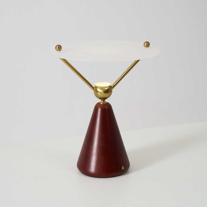 Gold and white table lamp seen at an angle against a plain ground