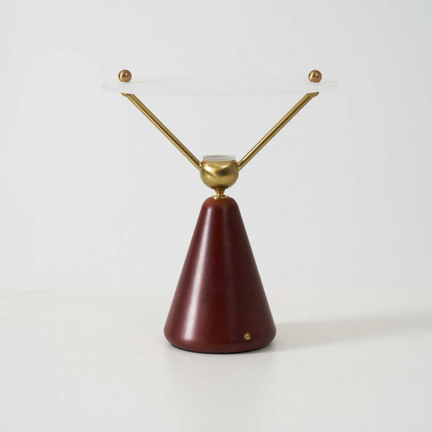 Gold and white table lamp seen from the side against a plain ground