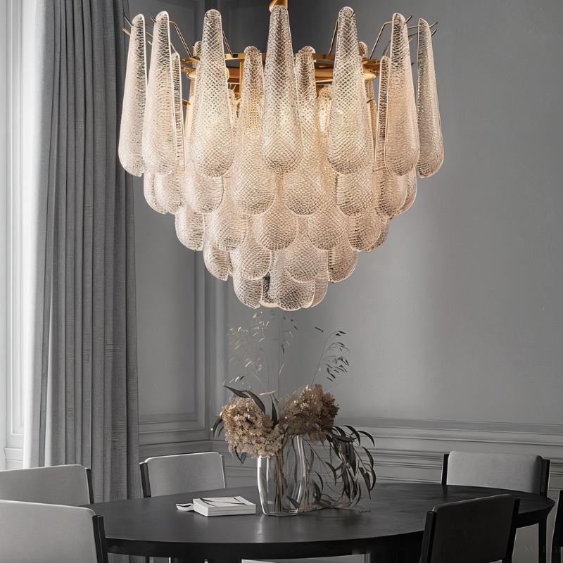 The fitting lit above a dark round dining table with chairs and dried flowers