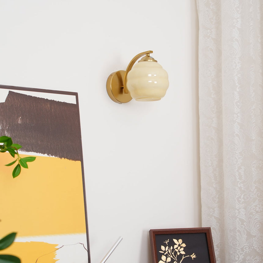 The gold sconce on a white wall above an abstract painting and a framed print
