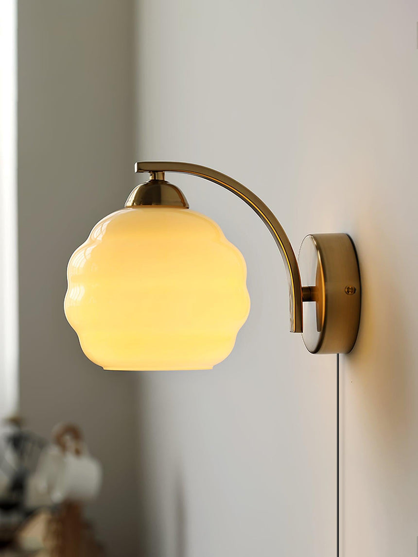 The gold plug-in sconce lit, its globe glowing warm and the cord below