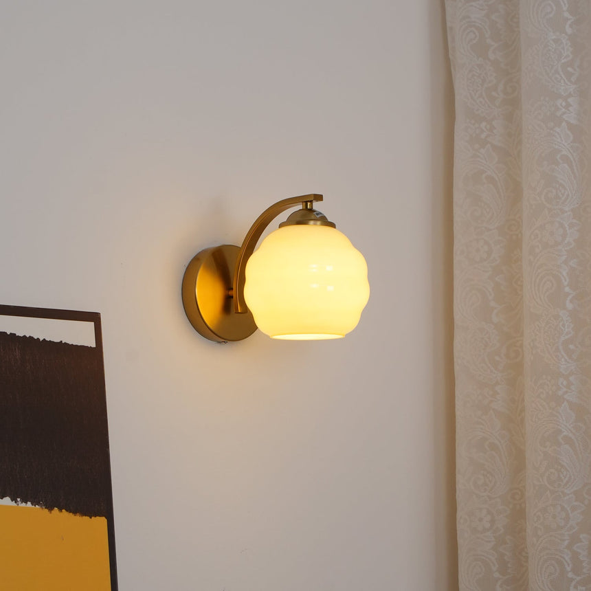 The gold sconce lit beside a sheer curtain, a painting at the lower edge