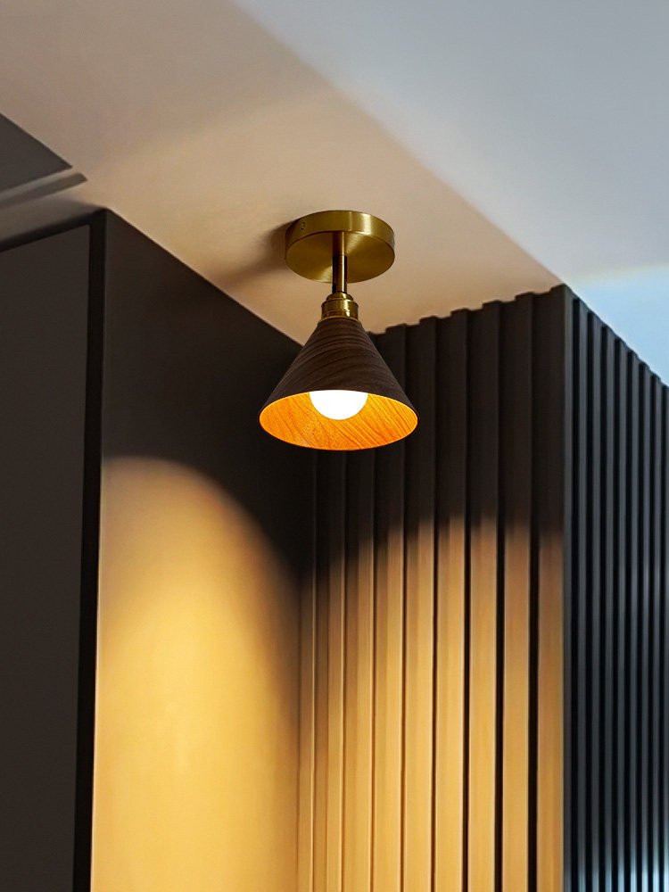 Cone ceiling light lit against a dark slatted wall, the shade glowing inside
