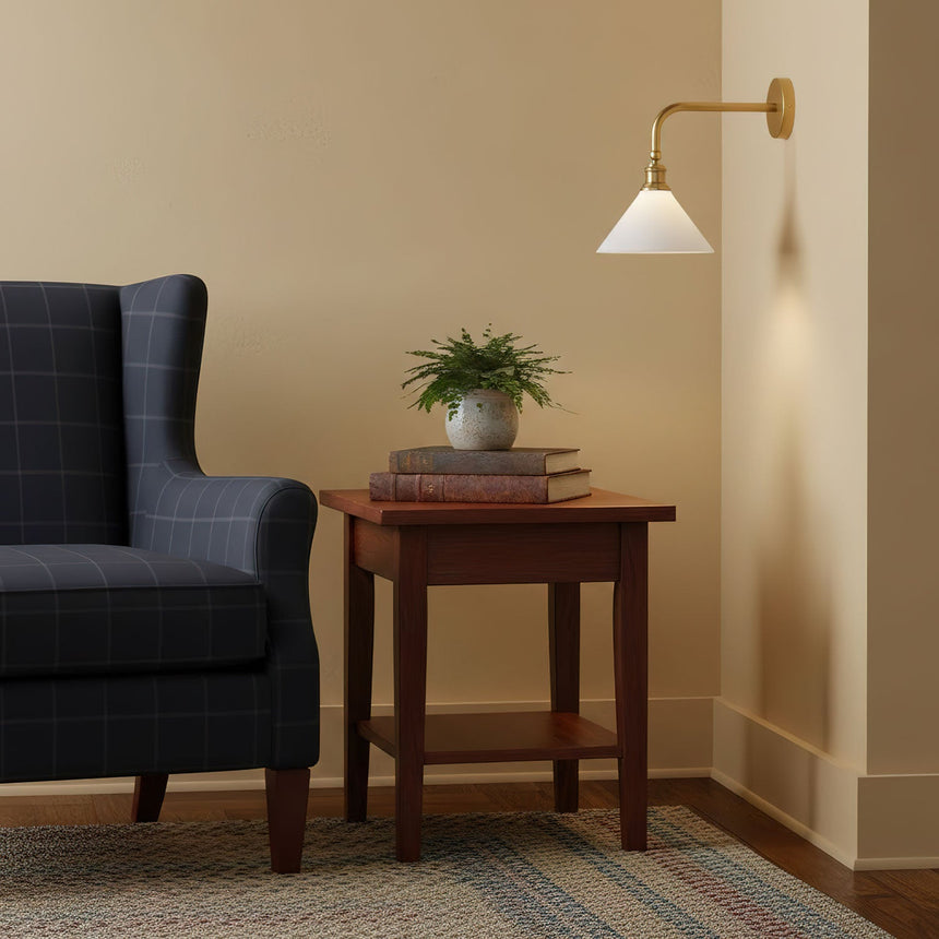 The sconce above a side table and a navy armchair in a warm corner