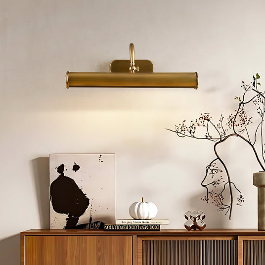 Copper tube lit above framed line drawings on a walnut and reeded glass sideboard
