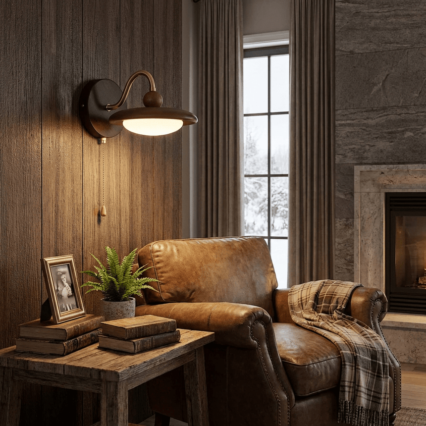 Sconce lit on a plank wall beside a leather chair and a stone fireplace