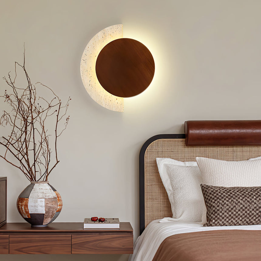 Sconce lit above a nightstand beside a bed with a leather headboard