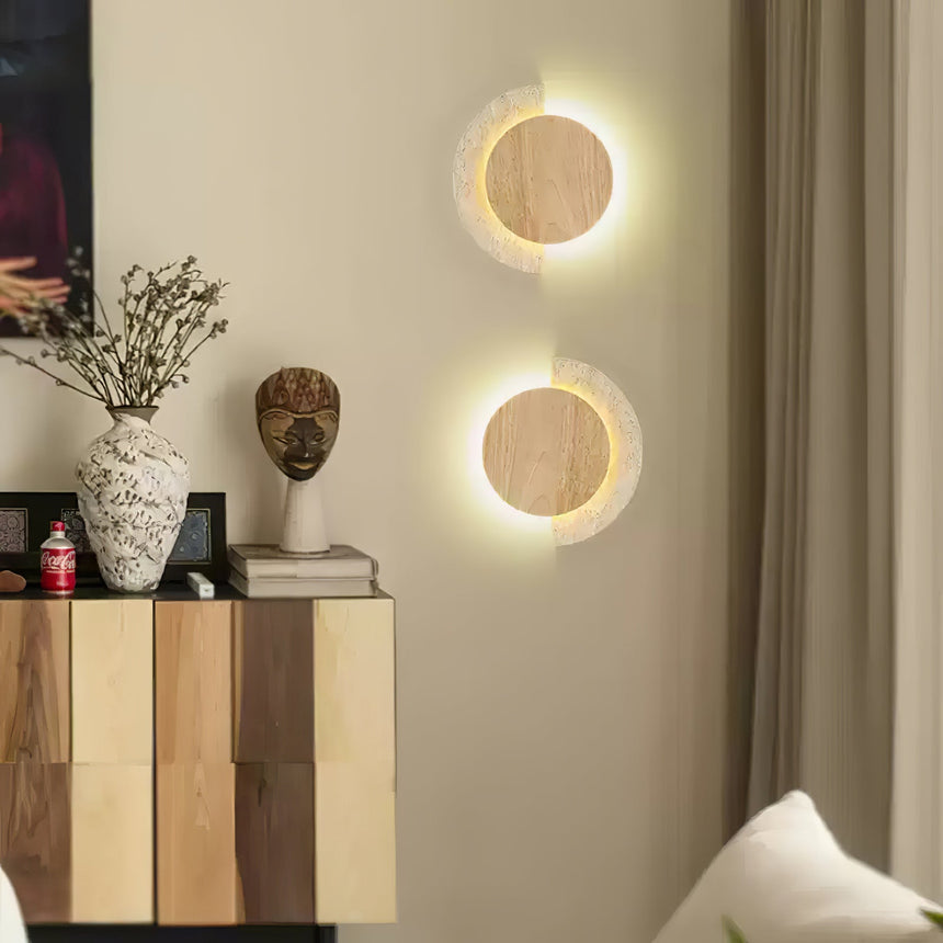 A pair of lit sconces on a living room wall above a wood sideboard