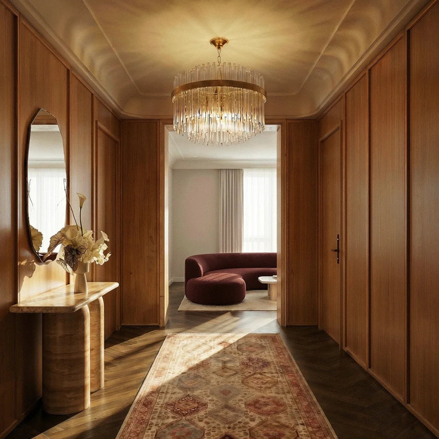 The lit fitting in a hallway above a runner rug, a console table and a round mirror