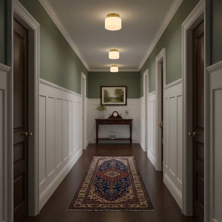Brass and white glass ceiling lights in a green corridor with a patterned runner