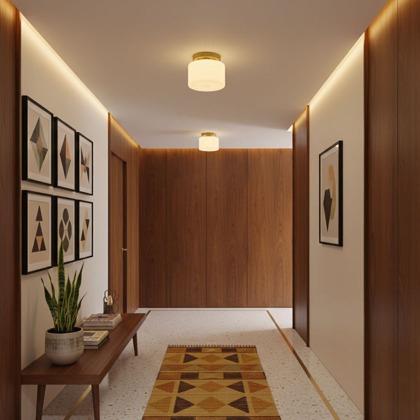 Brass and white glass ceiling lights in a wood paneled corridor with framed art