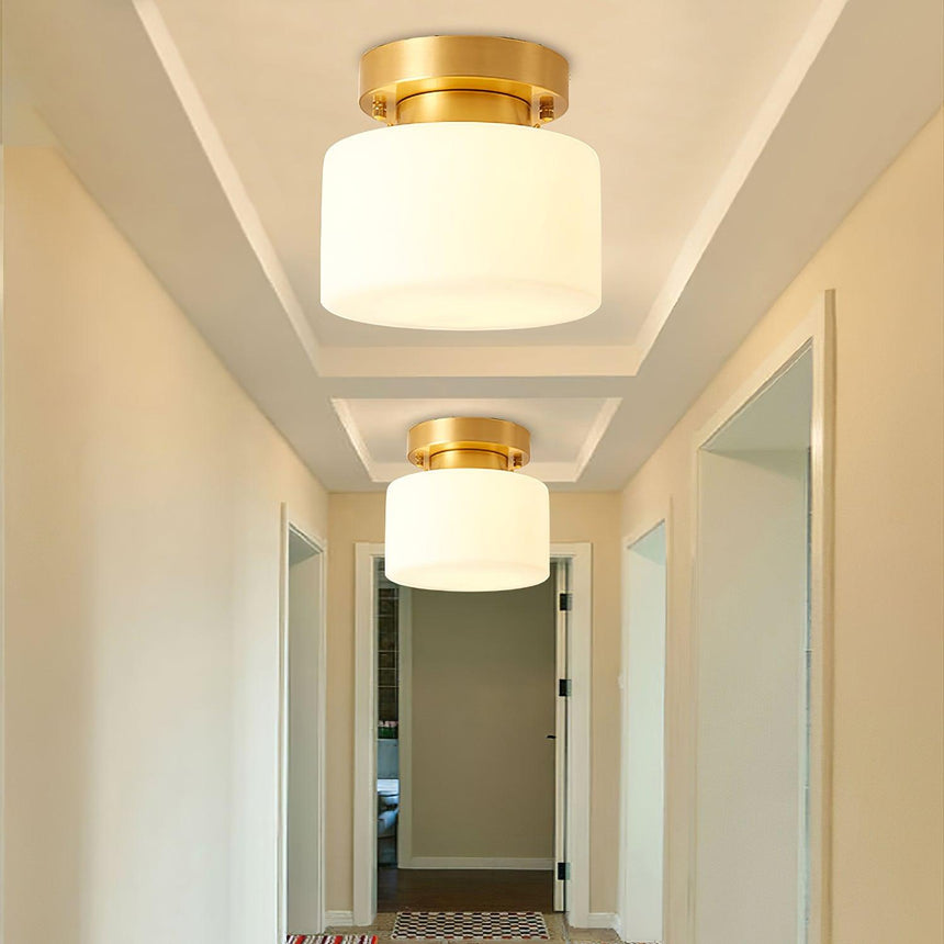 Two brass and white glass ceiling lights in a corridor with pale doors