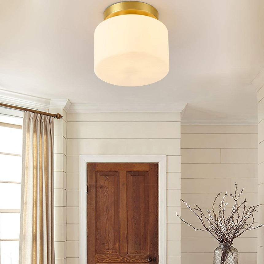 Brass and white glass ceiling light beside a wood door and a curtained window