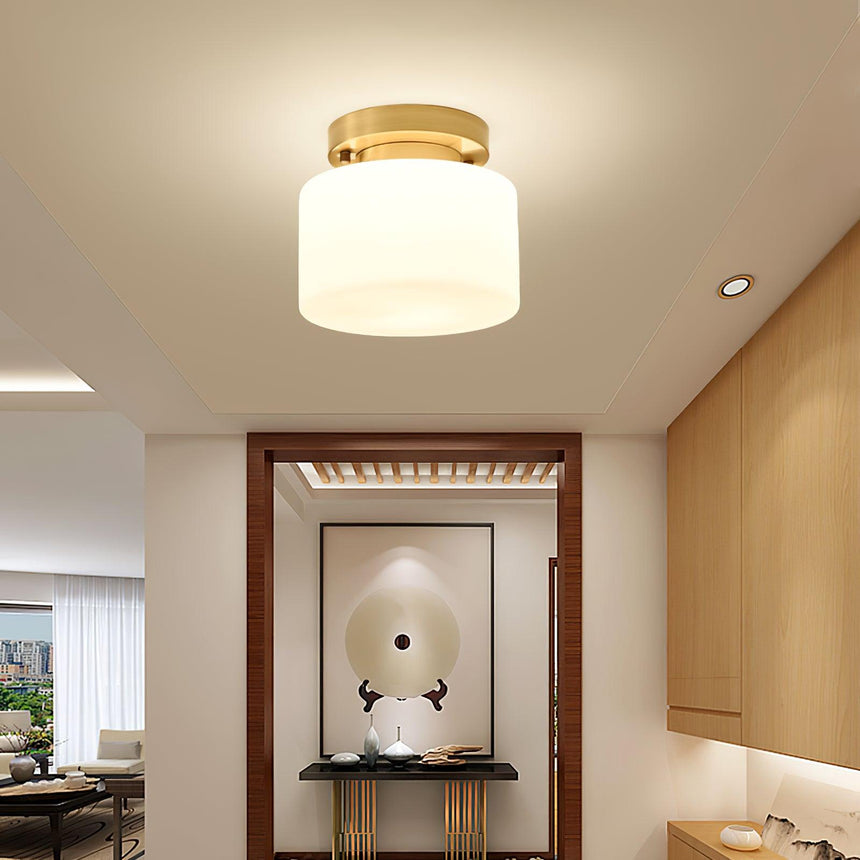 Brass and white glass ceiling light above a hallway niche with wood trim