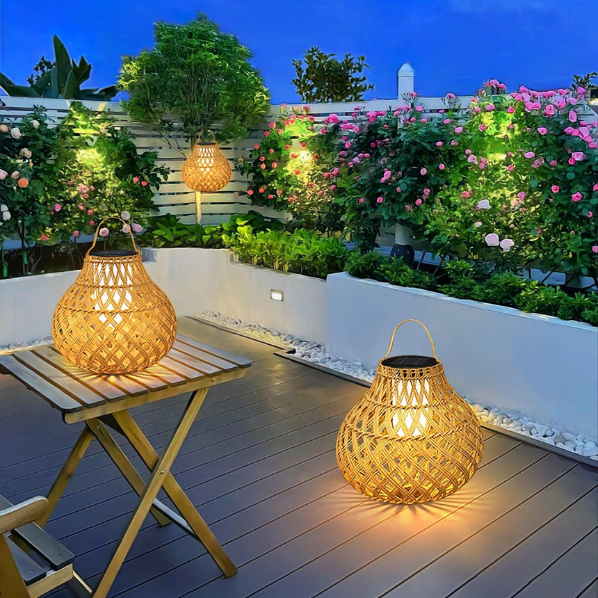 Lanterns lit on a roof garden beside a folding table and flowering shrubs