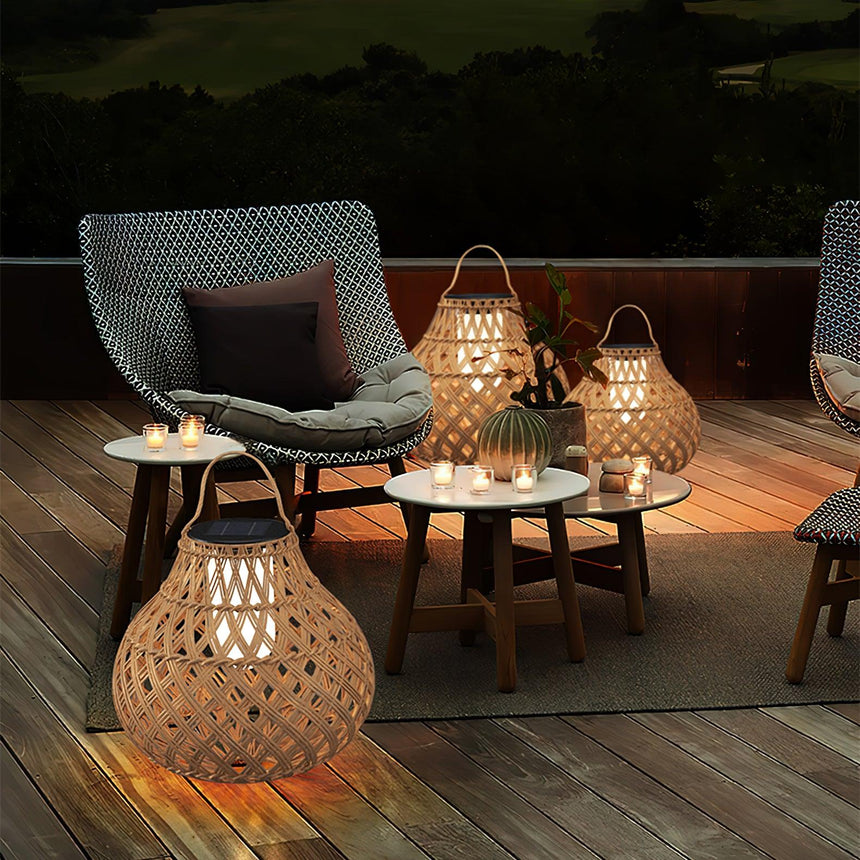 Lanterns lit on small tables on a terrace beside chairs and a lawn
